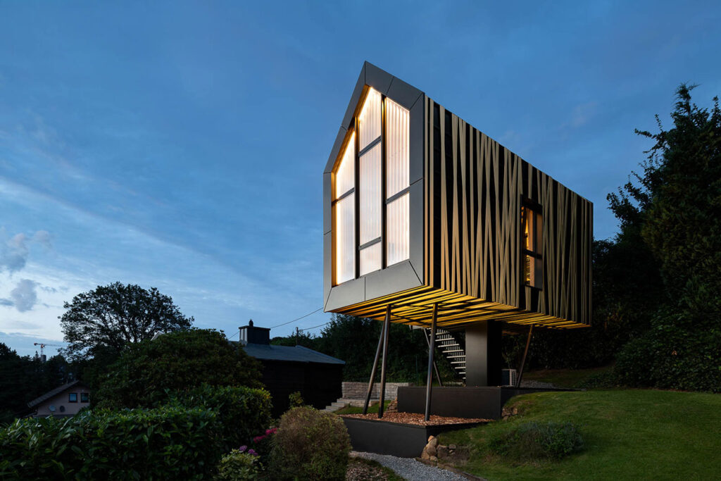 Design Baumhaus in Wuppertal bei Nacht mit beleuchteter Glasfassade