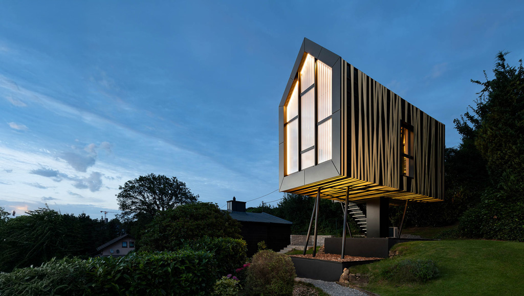 Design Baumhaus in Wuppertal bei Nacht mit beleuchteter Glasfassade